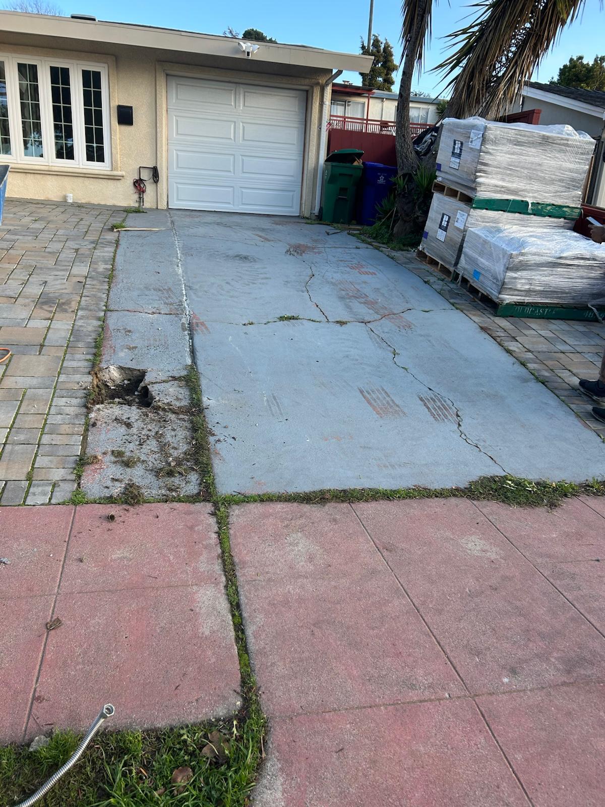 Before: cracked concrete driveway with materials staged on site